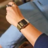 Casio CA-500WEG-1A vintage unisex ručni sat na ruci zene sa crnim brojčanikom i zlatnom narukvicom, savršen za stilizovane i funkcionalne prilike