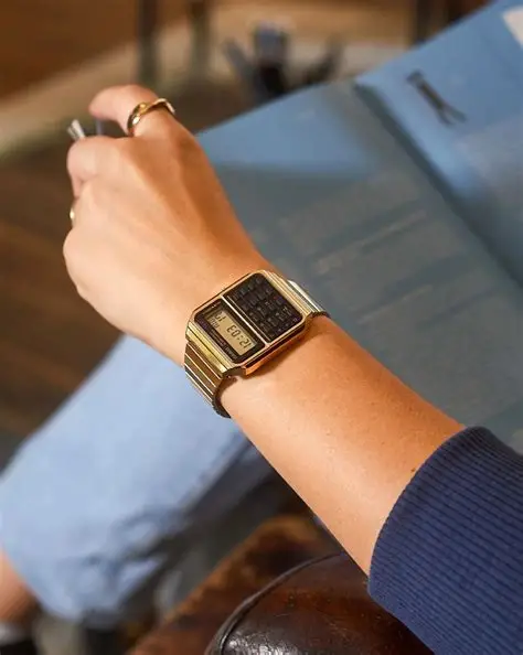 Casio CA-500WEG-1A vintage unisex ručni sat na ruci zene sa crnim brojčanikom i zlatnom narukvicom, savršen za stilizovane i funkcionalne prilike