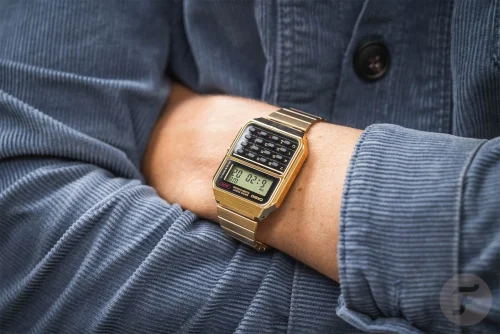 Casio CA-500WEG-1A vintage unisex ručni sat na ruci muskarca sa crnim brojčanikom i zlatnom narukvicom, savršen za stilizovane i funkcionalne prilike