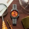 Seiko SSK005K1 – 5 Automatic GMT sat ambijentalna slika sat na stolu, sa narandžastim brojčanikom i srebrnom narukvicom, idealan za svakodnevno nošenje i aktivnosti na vodi