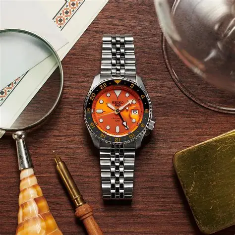 Seiko SSK005K1 – 5 Automatic GMT sat ambijentalna slika sat na stolu, sa narandžastim brojčanikom i srebrnom narukvicom, idealan za svakodnevno nošenje i aktivnosti na vodi