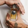 Elegantna bočica parfema Dolce&Gabbana Devotion Pour Homme EDP u rukama muskarca sa tamnim tonovima i zlatnim detaljima
