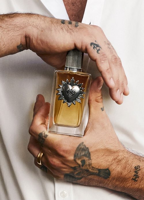 Elegantna bočica parfema Dolce&Gabbana Devotion Pour Homme EDP u rukama muskarca sa tamnim tonovima i zlatnim detaljima