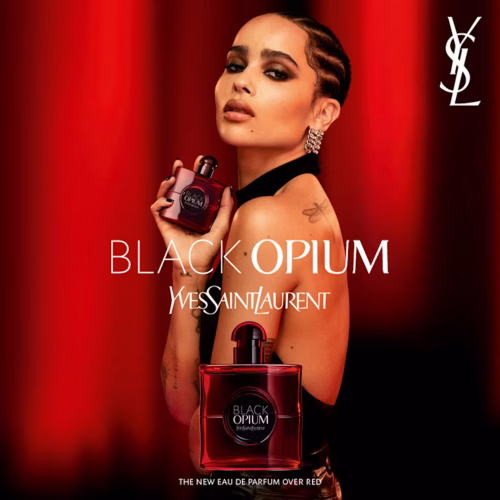YSL Black Opium Over Red ženski parfem – sladak, zavodljiv i moderan miris prikazan u elegantnom i urbanom ambijentu koji naglašava ženstvenost i samopouzdanje. Zena drzi parfem, crvena pozadina i bela slova brenda