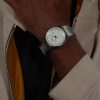 Muškarac nosi Hugo Boss 1514186 CANDOR automatski sat sa srebrnim kućištem i čeličnom narukvicom na zglobu, elegantan poslovni stil