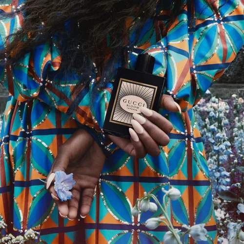 Original Gucci Bloom Intense Eau de Parfum za žene u ruci zene u plavoj haljini sa cvetovima